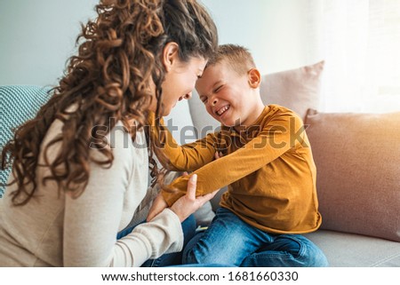 Mother and son playing in a living room. Spending quality time togather. Mother and son laughing. Exited mom and son are entertaining in living room. Parents are playing with children at home concept