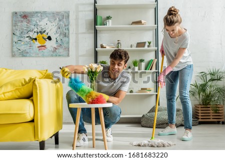 happy man and woman doing spring cleaning in apartment Royalty-Free Stock Photo #1681683220