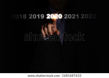 Businessman hand touching 2020 year on black background. It is symbol of fiscal and business year change.