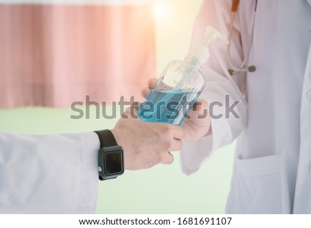 Doctor hand  gives a bottle of alcohol gel to another doctor  for used to wash hands  and prevention coronavirus outbreak .