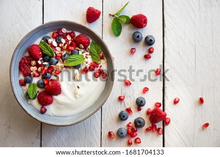 Yogurt with fresh fruit and berries (raspberry, pomegranate, blueberry) and mint for healthy breakfast Royalty-Free Stock Photo #1681704133