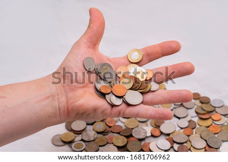 Hand dropping different coins on white background