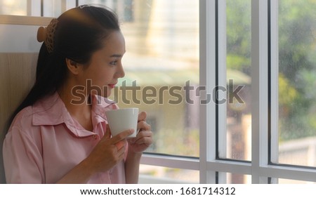 The portrait picture of Asian female working at home, looking outside the window and drinking a cup of coffee, close up view, startup small business owner idea, businesswoman successful concept