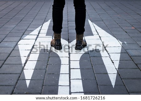 Make decision which way to go. Walking at directional sign on road. Choice concept with human legs and arrow symbol on street
