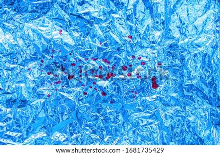 Red color droped on blue foil background, grunge metal texture for backdrop or wallpaper. Top view with copy space background.