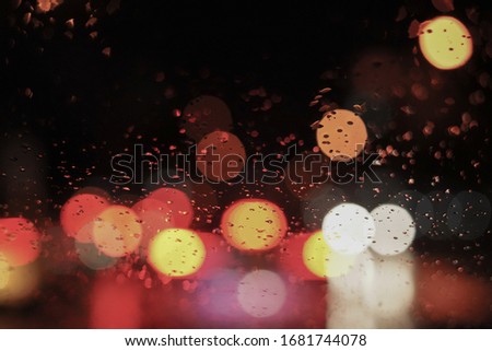 Beautiful street and city view light and illuminated bokeh background in the night and raining with water drop on the window feel lonely and chill out