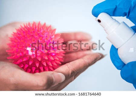 Scientific with gloves use sanitizer for Corona virus. Female hands holding a Coronavirus red model. Preventive measures against Covid-19 infection. Аntibacterial gel alcohol-based hand-washing spray