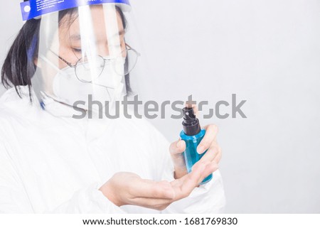 Nurse or doctor in a protective suit, a blue hand sanitizer from a bottle. Antibacterial gel with alcohol-based hand-washing spray.