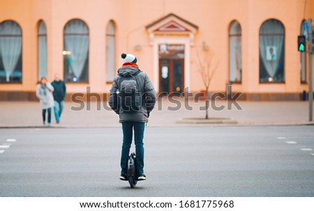 Electric unicycle. Man rides on mono wheel crosswalks on the road. Guy driving on self-balancing personal transporter with single wheel. Royalty-Free Stock Photo #1681775968
