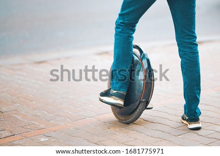 Personal transportation gadget, electric unicycle. Man rides on monowheel. Guy driving on self-balancing personal transporter with single wheel. Urban electric transport Royalty-Free Stock Photo #1681775971