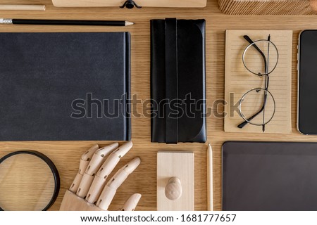 Stylish flat lay business composition on the wooden desk with notebooks, stample, notes and office supplies in modern concept of home office.
