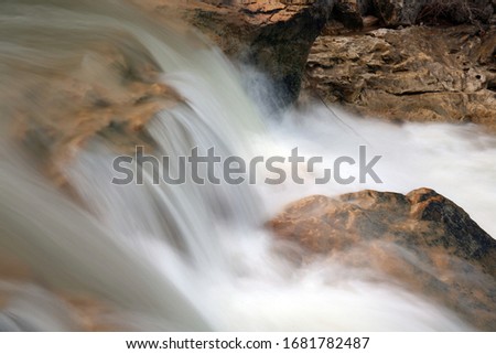 Detail of silky water flowing between the rocks of a river.
