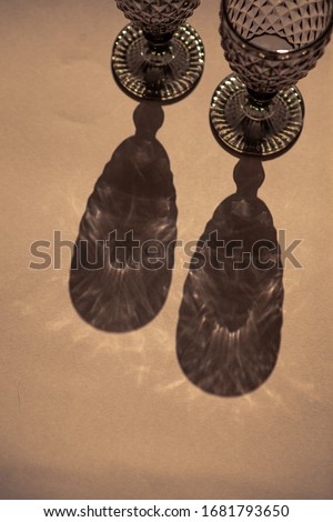 Beautiful glass goblets on a beige isolated background. Sunlight penetrates glass goblets