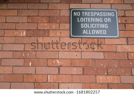 No trespassing sign on brick wall of downtown business