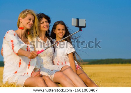 lovely family taking a selfie on a haystack against a blue sky and a wheat field