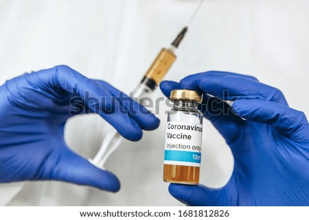 A doctor in a white robe and blue gloves holds a syringe with a coronavirus vaccine. Injection of the vaccine from covid-2019. Pandemic coronavirus 2020. vaccine test.