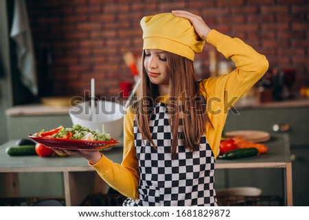 Young teen girl preparing salad for breakfast at the kitchen