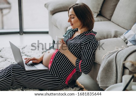 Young pregnant woman working on computer at home