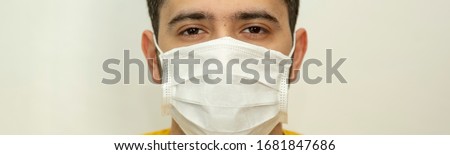 COVID-19 Stop coronavirus. Closeup studio portrait of a young guy laid on a medical mask against coronavirus isolated on a white background. Panoramic banner concept.