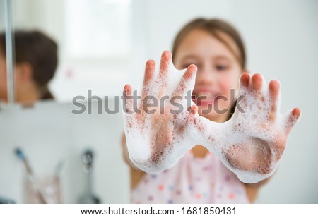 Little girl washing hands with water and soap in bathroom. Happy kid showing soapy palms. Hands hygiene and virus infections prevention.  Royalty-Free Stock Photo #1681850431