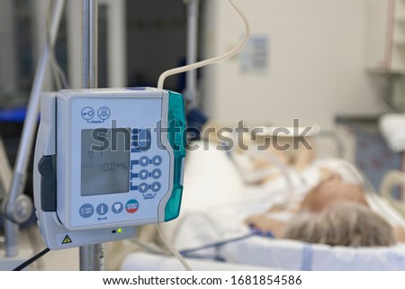 A small, lightweight, portable enteral feeding pump in ICU in hospital, on background patient in bed connected to medical ventilator in ICU in hospital Royalty-Free Stock Photo #1681854586