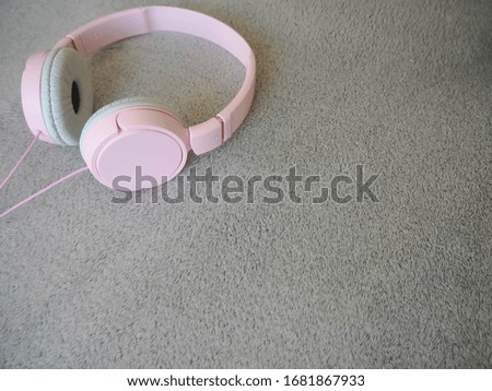 Large pink headphones with a cord lie on a gray structural background