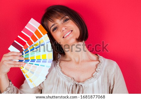 woman next to a red wall looking to a color paint palette (selective focus)