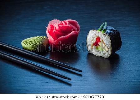 Sushi roll, ginger, wasabi and chopsticks on black tableboard. Japanese food concept. Still life close up food photo