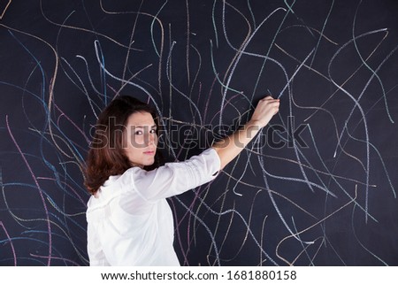 Stressed woman writing in the chalkboard lots of crazy lines