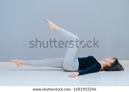 Beautiful young woman working out at home, doing yoga exercise on wooden floor, lying in Shavasana Corpse or Dead Body Posture , resting after practice, meditating, breathing. Full length, top view Royalty-Free Stock Photo #1681903246