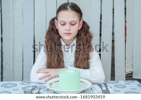A roll of toilet paper lies on a plate. Girl wants to eat it with a knife and fork.