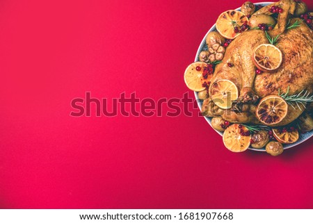 Roasted chicken with oranges, rosemary and cranberries on plate over concrete background. Traditional Thanksgiving or Friendsgiving holiday celebration dish. Friends or family dinner. Festive