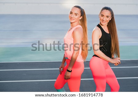 Sports and fitness outside the gym. Young fit women with perfect bodies in sportswear train together outdoors on playground. Sportive and healthy lifestyle, street work out, training, exercise concept