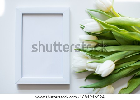 White blank frame on white background with tulips flower. Minimalistism background. Mock up frame. Summer or travel concept. Copy space