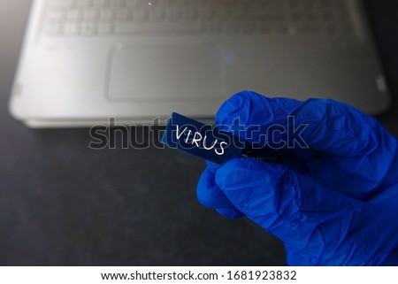 Artificially Created Virus. Hand in Medical Glove Holding Infected Memory Card Computer Blurred Dark Desk Background
