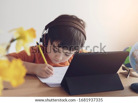 Kid self isolation using tablet for his homework,Child doing using digital tablet searching information on internet during covid 19 lock down,Home schooling,Social Distance,E-learning online education Royalty-Free Stock Photo #1681937335