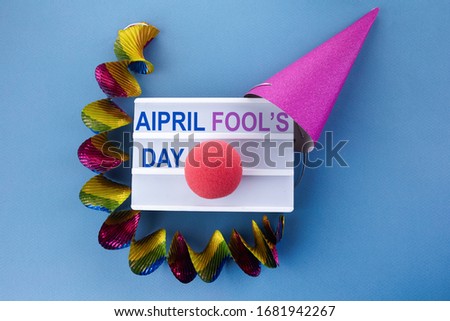Party cap and light box with phrase April fool's day on blue bckground