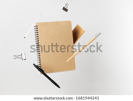 Stationery set. Levitation of notepad, pencils, pen, sticker and binder clips. Copy space on notebook and notes. Writing tools. Office supplies. Isolated on gray backdrop Royalty-Free Stock Photo #1681944241