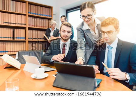 Young but diligent Lawyers in their law firm working on computer with books in background