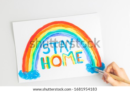 Kid painting during quarantine at home. Rainbow with words Stay at home. Social media campaign for coronavirus prevention