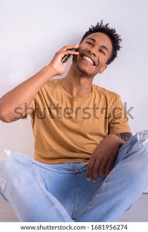 African american millennial man using technology. Young male texting with smart phone connected to internet isolated on white background with vertical copyspace. Technology musical concept indoors.