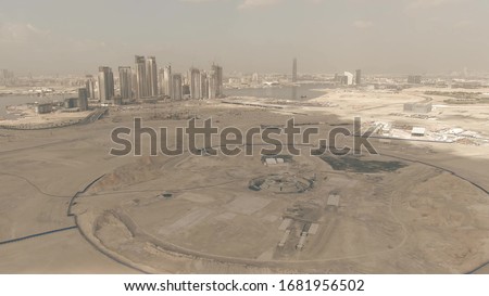 Aerial shot of a desert construction site with Dubai's skyscrapers as a background, UAE