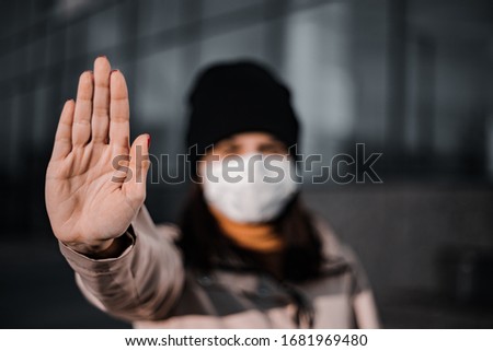 Dark tones girl showing stop sign with her hand to a coronavirus worldwide pandemia. Focus on a palm saying no to a Chineese virus Covid-19. nCov2019 epidemia.