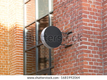 Blank black outdoor round box mockup brick wall mounted. Empty street signage hanging on emporium mock up. Clear circular banner for club restaurant mokcup template.