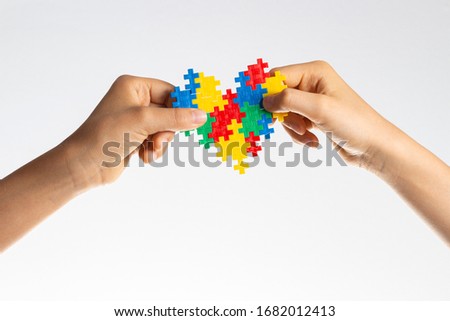 World autism awareness day concept. Children hands holding colorful puzzle heart on white background