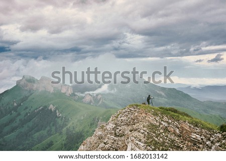 Photographer looking into viewfinder of dslr digital camera stand on tripod. Artist photographing mountain and cloudy landscape. Man check picture on screen his camera while shooting nature pictures