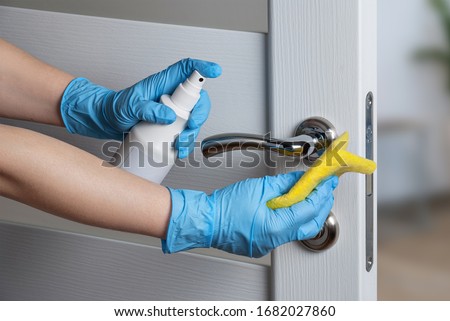 Cleaning door handles with an antiseptic during a viral epidemic Royalty-Free Stock Photo #1682027860