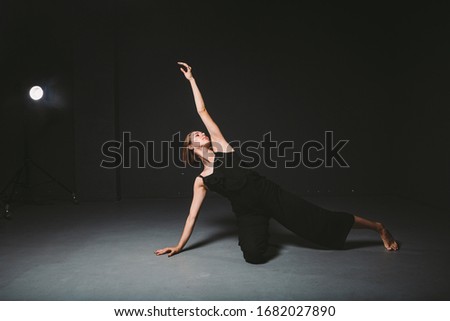 Portrait of a beautiful woman dancing on black background. Ballet and contemporary dancer dancing on dark backdrop. Contemporary Art. Plastic and flexible girl in black clothes posing on a black wall.