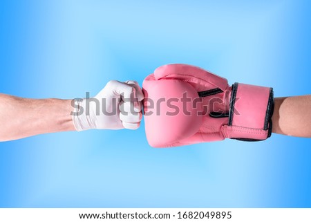 Nurses and doctors fight with the coronavirus / covid19. nurse's fist with a white glove strikes a fist with a pink glove, in a blue background Royalty-Free Stock Photo #1682049895