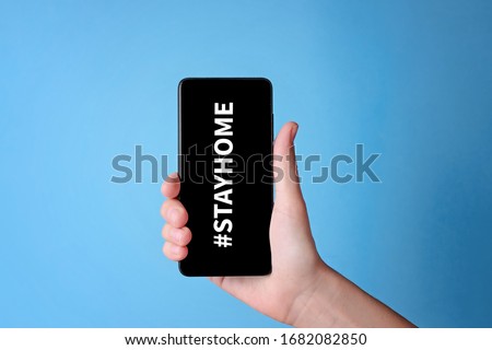 Call to stay home during a coronavirus covid-19 epidemic to protect against the virus. Smartphone with hashtag stayhome on blue background Royalty-Free Stock Photo #1682082850